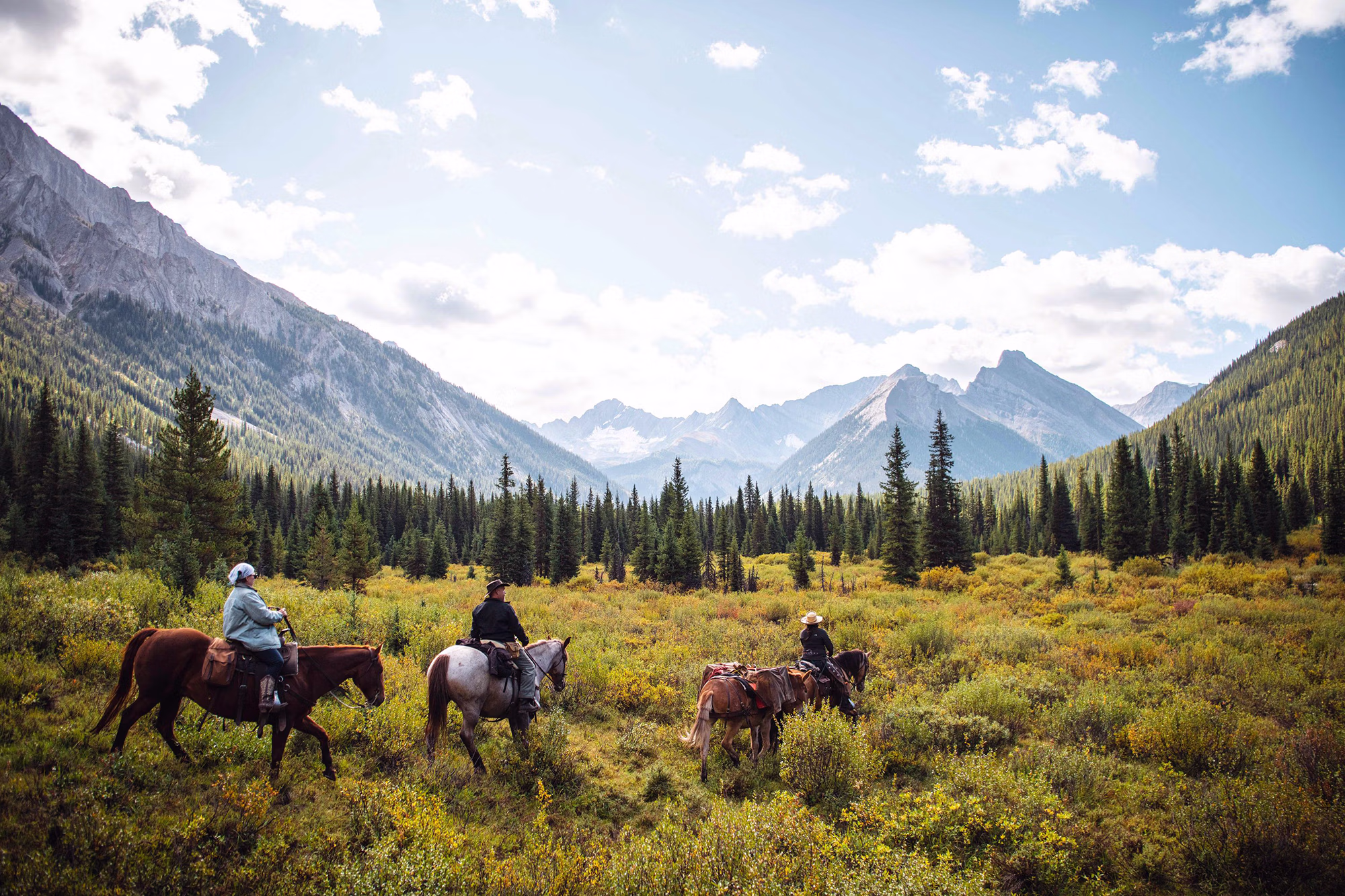Un groupe de cavaliers à cheval traversant les paysages alpins escarpés emblématiques du parc national de Banff.