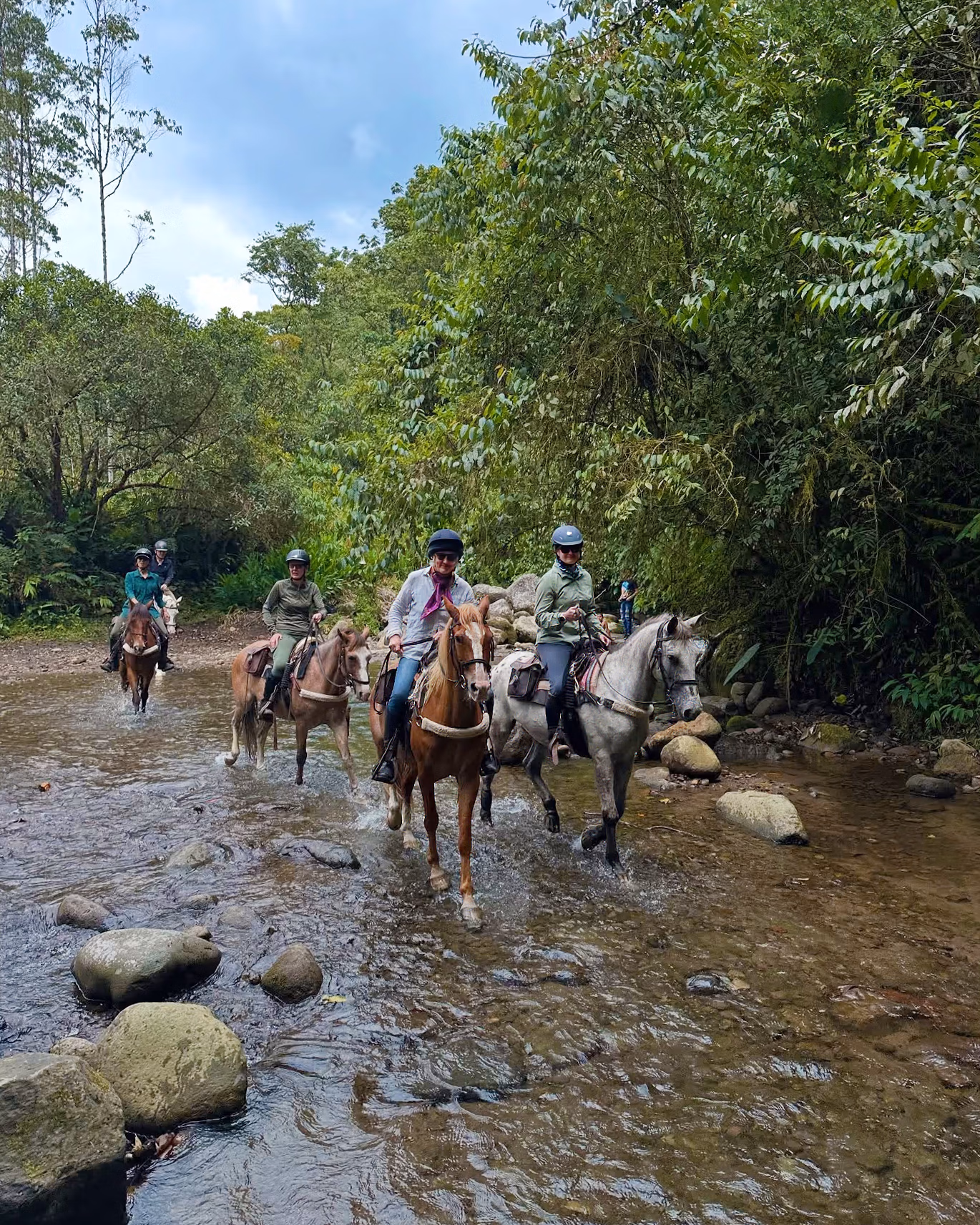 De nombreux cavaliers avancent ensemble dans le lit d’une rivière.