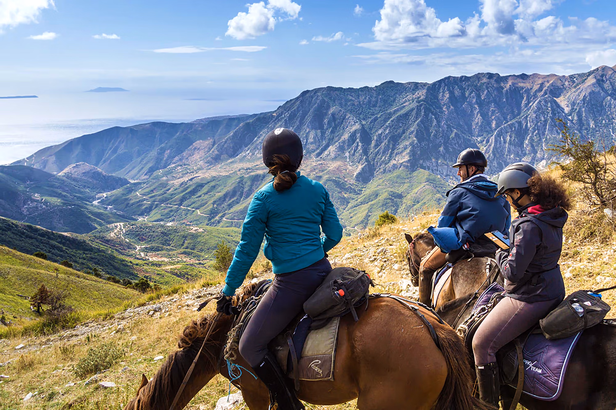 Un groupe de cavaliers fait une pause sur une crĂŞte en altitude, surplombant les paysages spectaculaires et sauvages des montagnes.