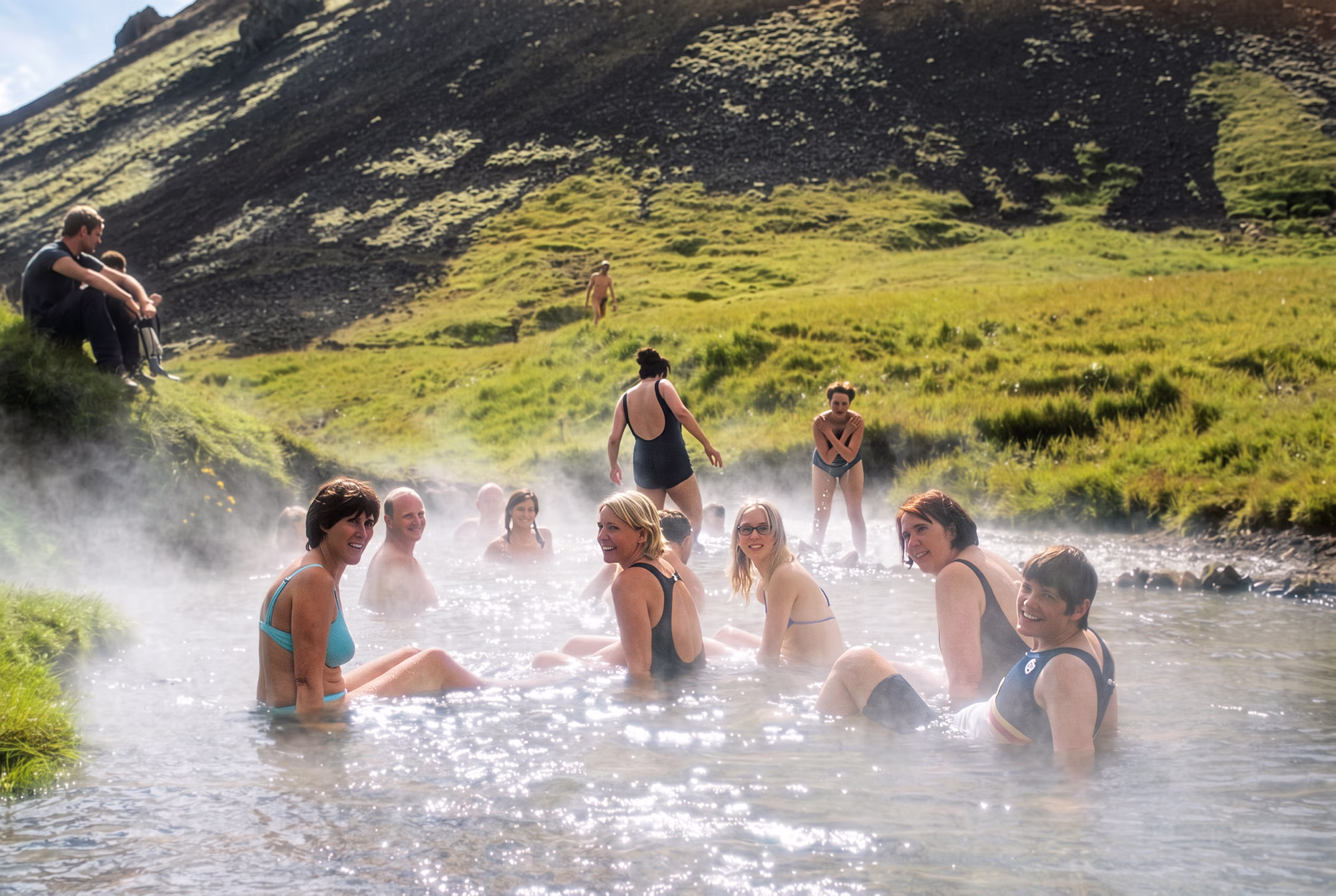 Un groupe de cavaliers fait une pause pour se détendre dans les eaux chaudes et fumantes d’une rivière géothermale.