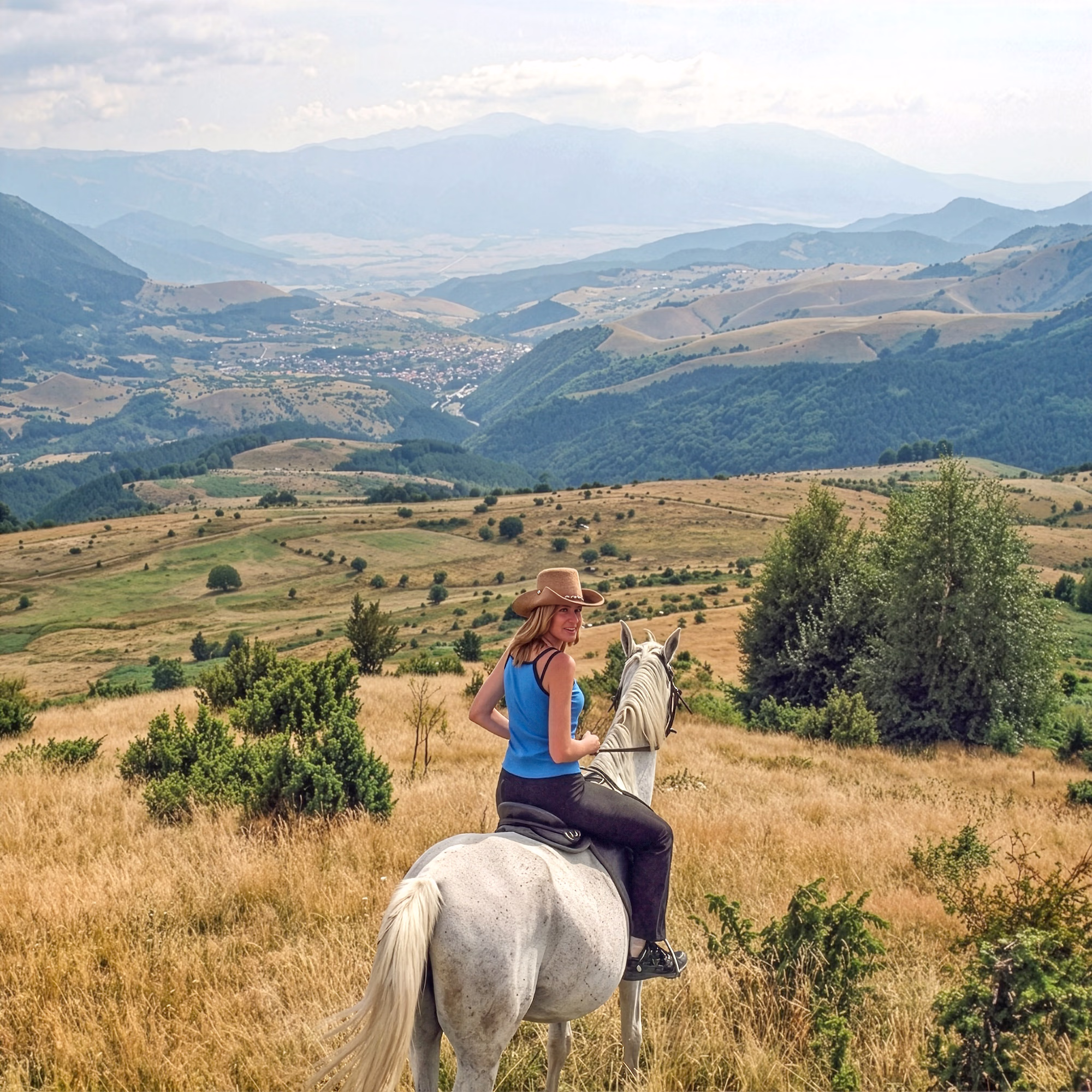 Une cavalière à cheval regarde par-dessus son épaule, avec les montagnes bulgares en toile de fond.
