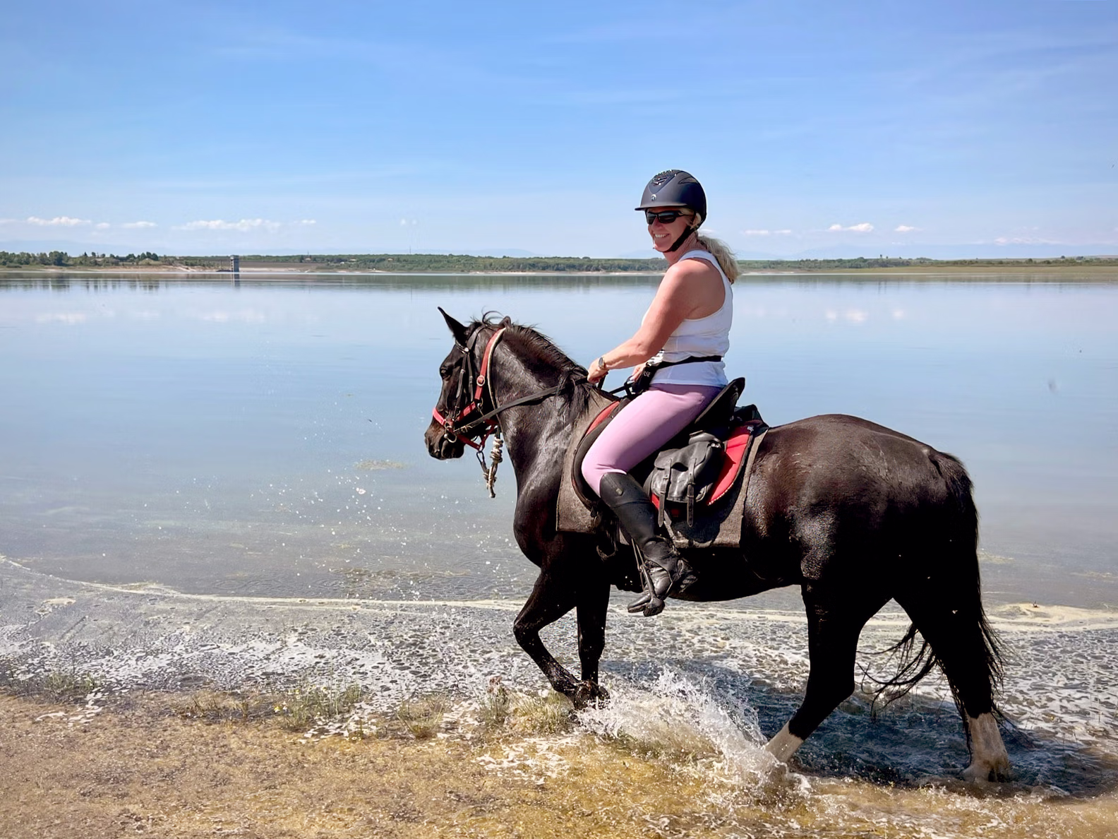 Une cavalière traverse une étendue d’eau à cheval lors d’une randonnée équestre.
