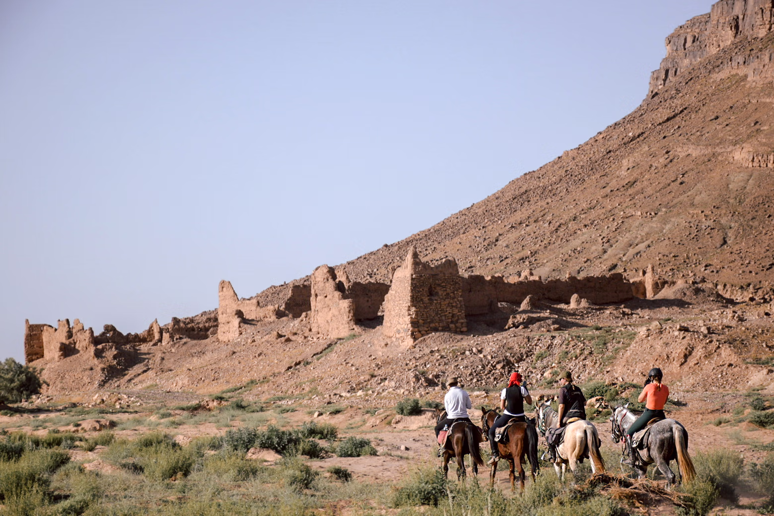 Un groupe de cavaliers s’approche des ruines d’anciens bâtiments en terre crue.