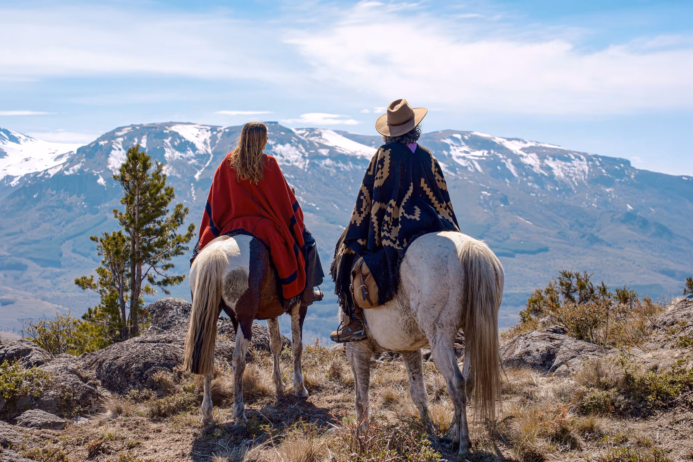 Deux cavaliers en haut d'une montagne en tenue traditionnelle de Patagonie.