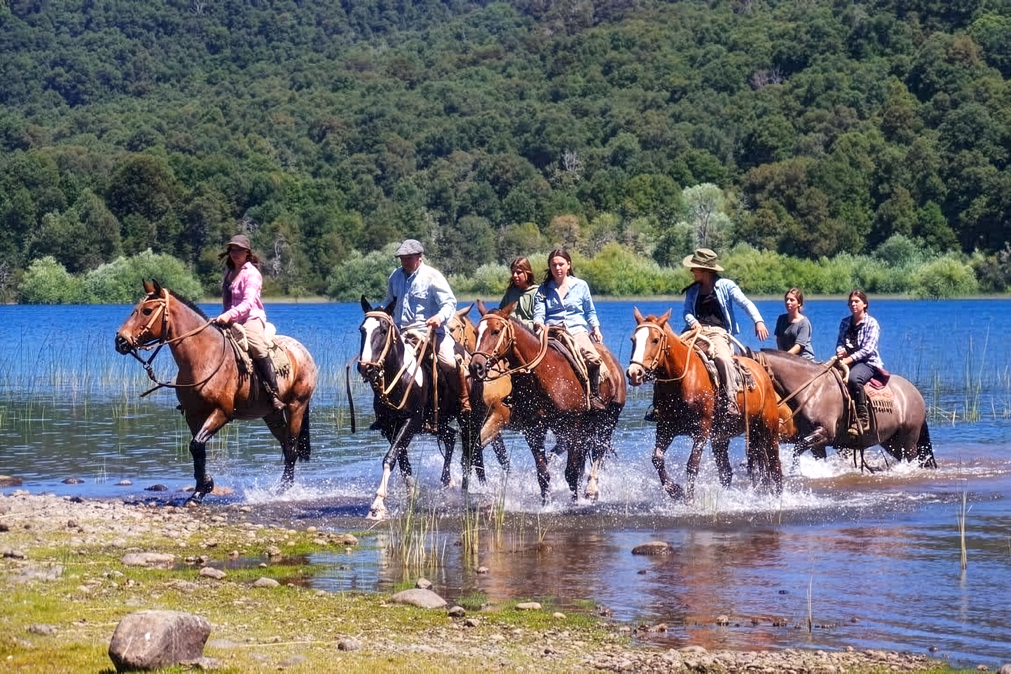 Un petit groupe de cavaliers sort de l’eau avec leurs chevaux pour rejoindre la rive en Patagonie.