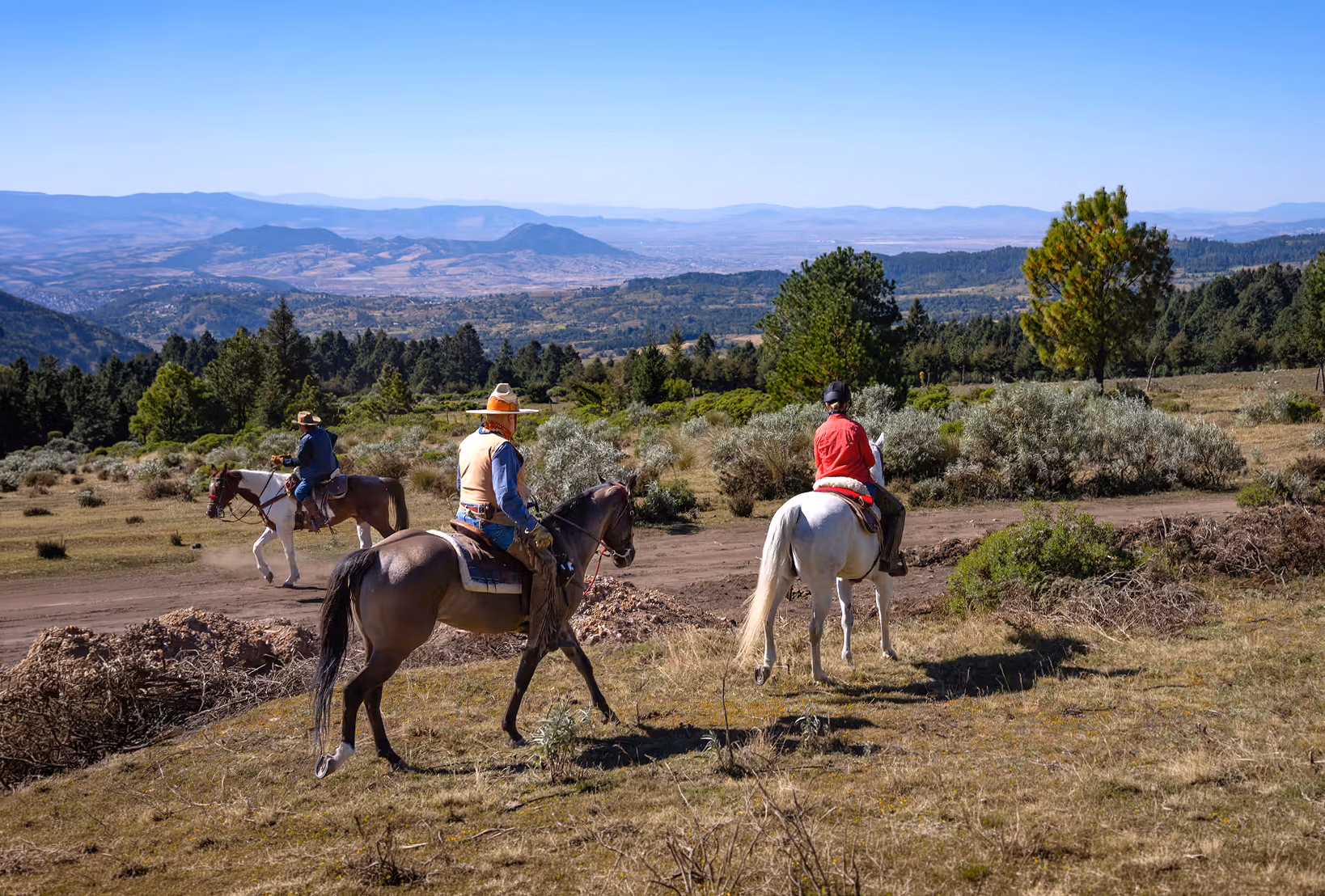 Trois cavaliers traversent un vaste paysage montagneux lors d’une randonnée équestre dans le centre du Mexique.