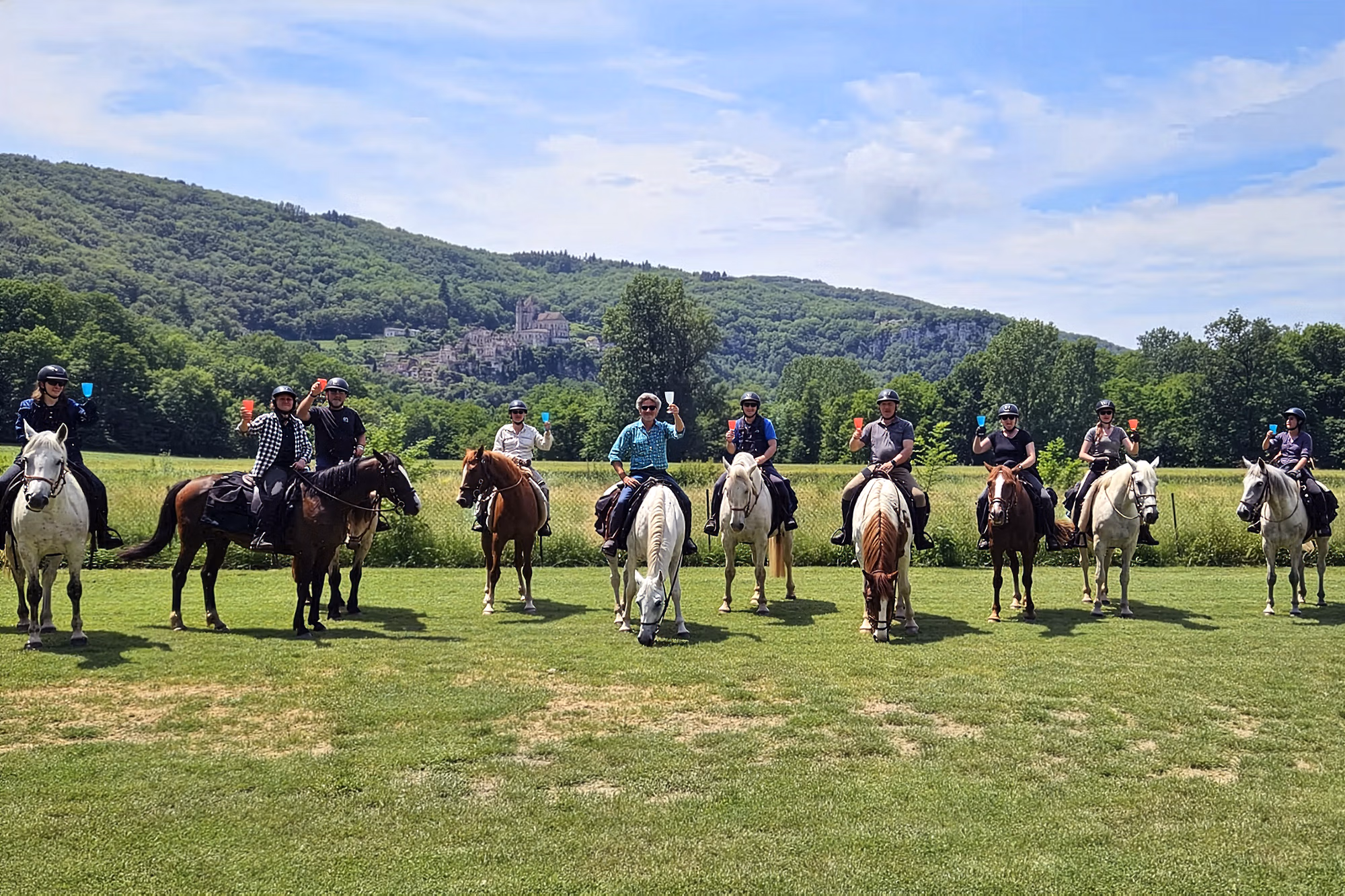 Un grand groupe de cavaliers pose pour une photo sur la Route des Vins de Sancerre, levant leurs verres pour trinquer.