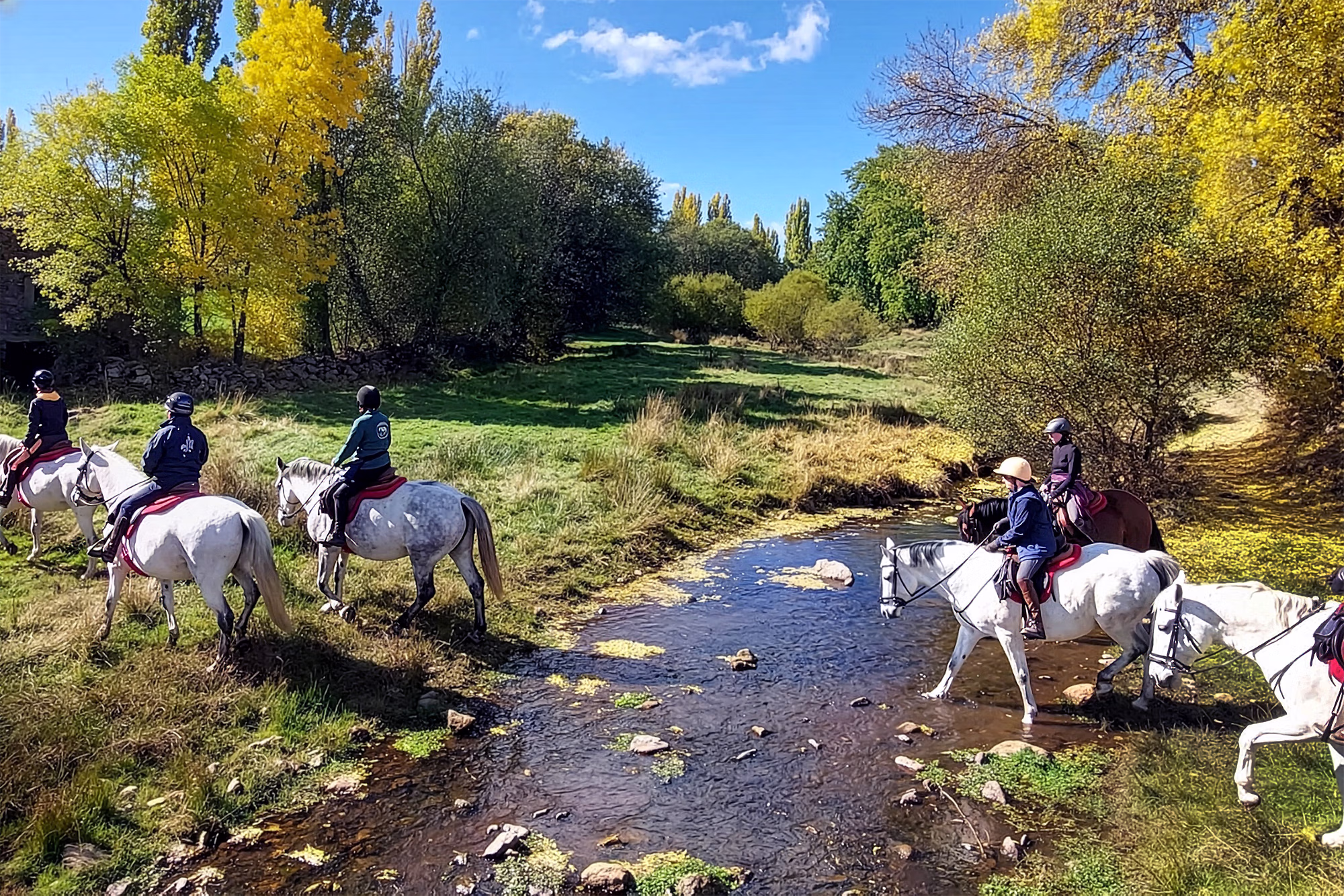 Un groupe de cavaliers traversant une rivière lors d’un séjour de randonnée équestre en Espagne.