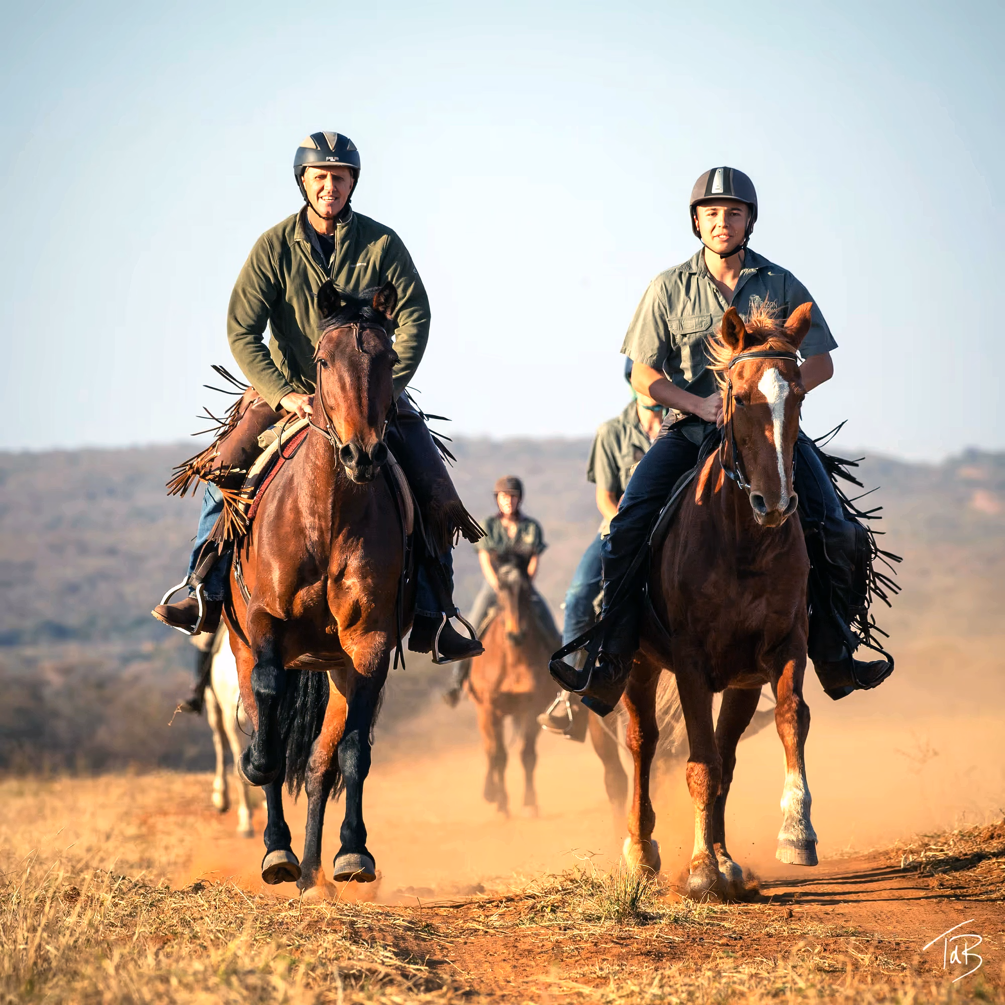Riders cantering in the South African bush on a riding safari