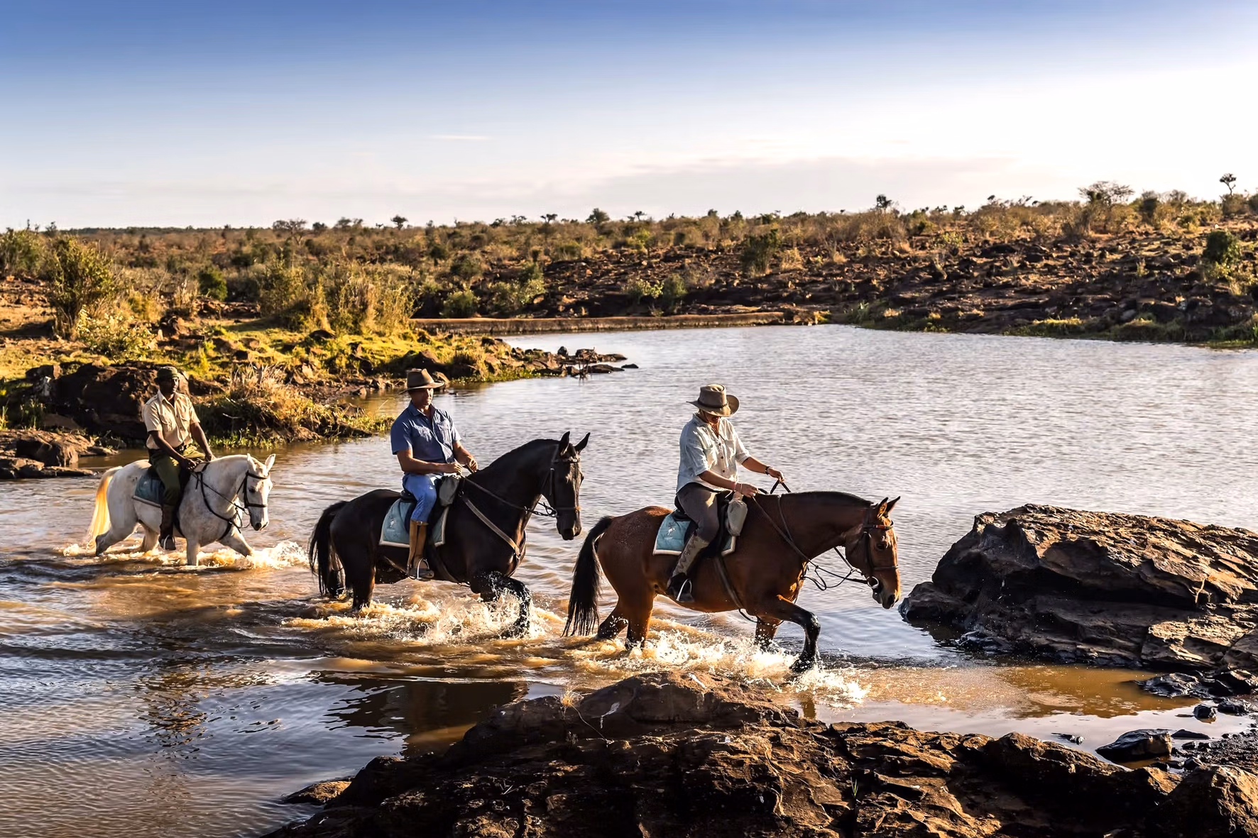 Des cavaliers traversent une rivière lors d’un safari équestre.