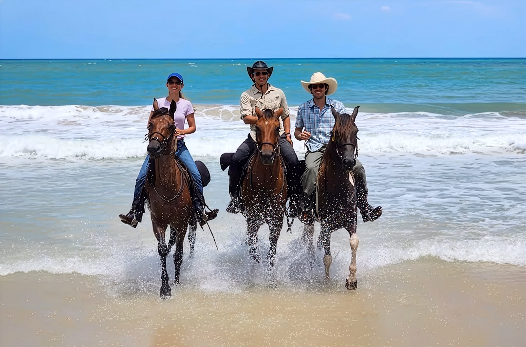 Trois cavaliers posent sur une plage ensoleillée lors d’une randonnée au Brésil.