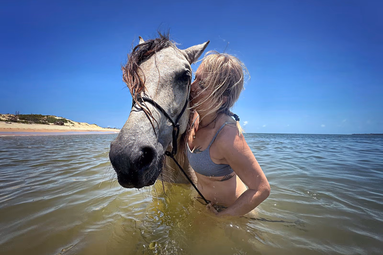 Une cavalière se baigne avec son cheval dans une eau rafraîchissante.