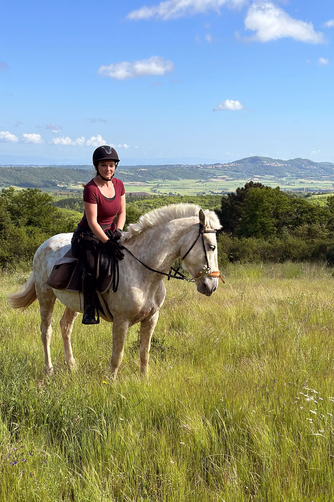 Une cavalière pose avec son cheval au milieu d’un pré verdoyant.