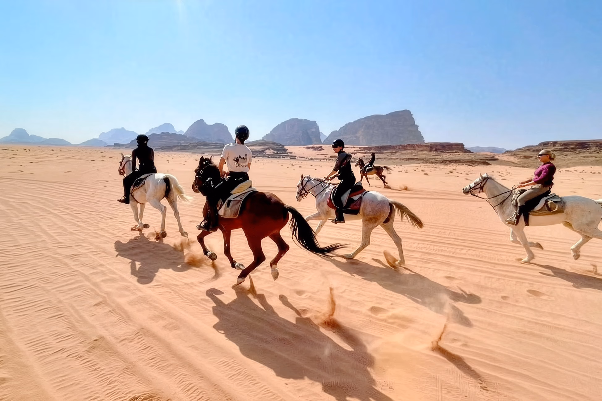 Un groupe de cavaliers galope dans le désert de Wadi Rum en Jordanie.