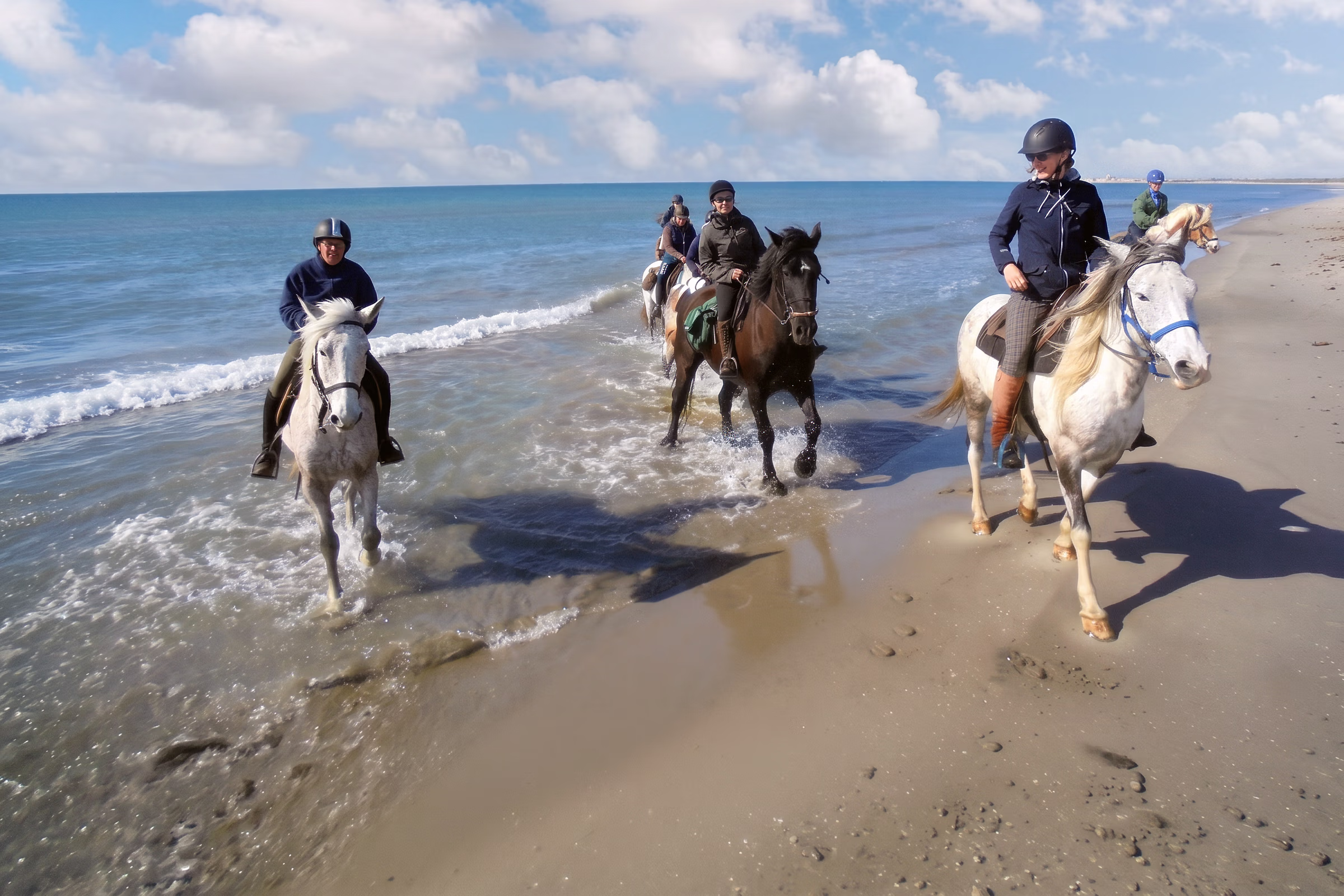 Cavaliers et chevaux sur une plage sauvage de Camargue lors d’un voyage à cheval dans le sud de la France.
