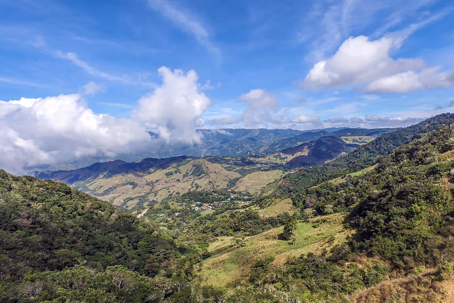 De vastes collines verdoyantes s’étendent sous un ciel bleu limpide dans les hautes terres montagneuses.