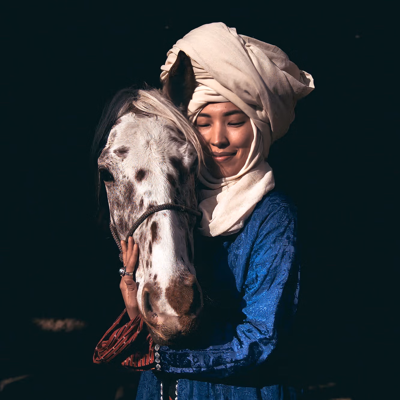 Une Kirghize en tenue traditionnelle caresse tendrement la tête d’un rare cheval Chaar Appaloosa.