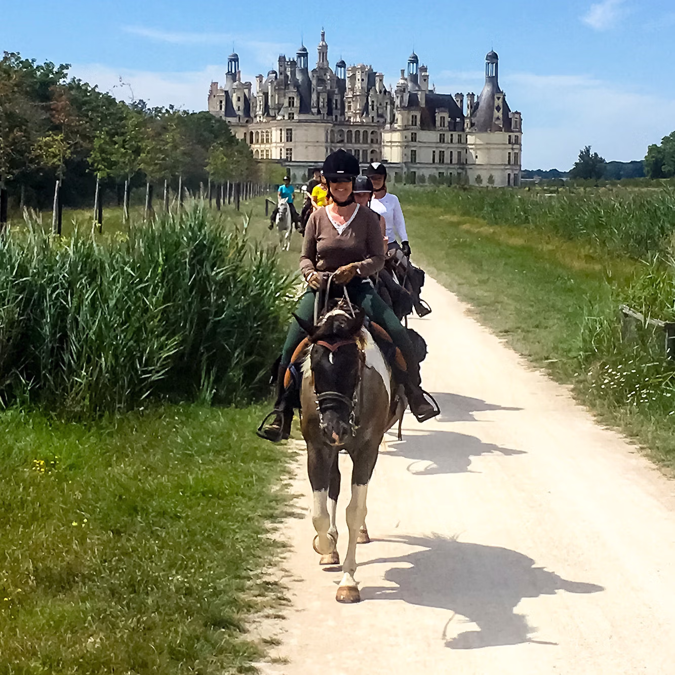 Cavalier a cheval sur un chemin avec un chateau au loin, et le ciel bleu