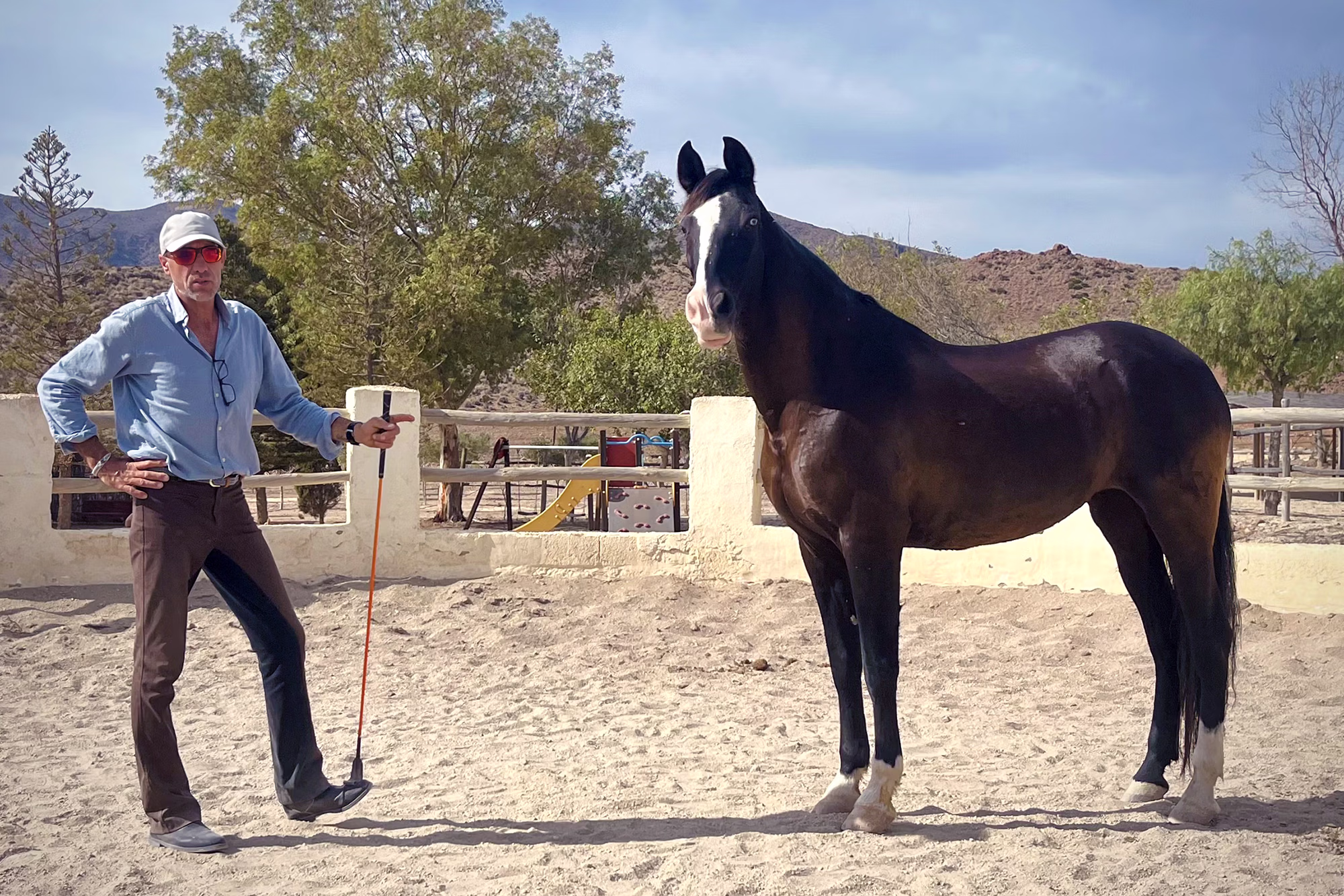 A dedicated horse whisperer shares a quiet, close moment of connection with his horse in an outdoor setting.