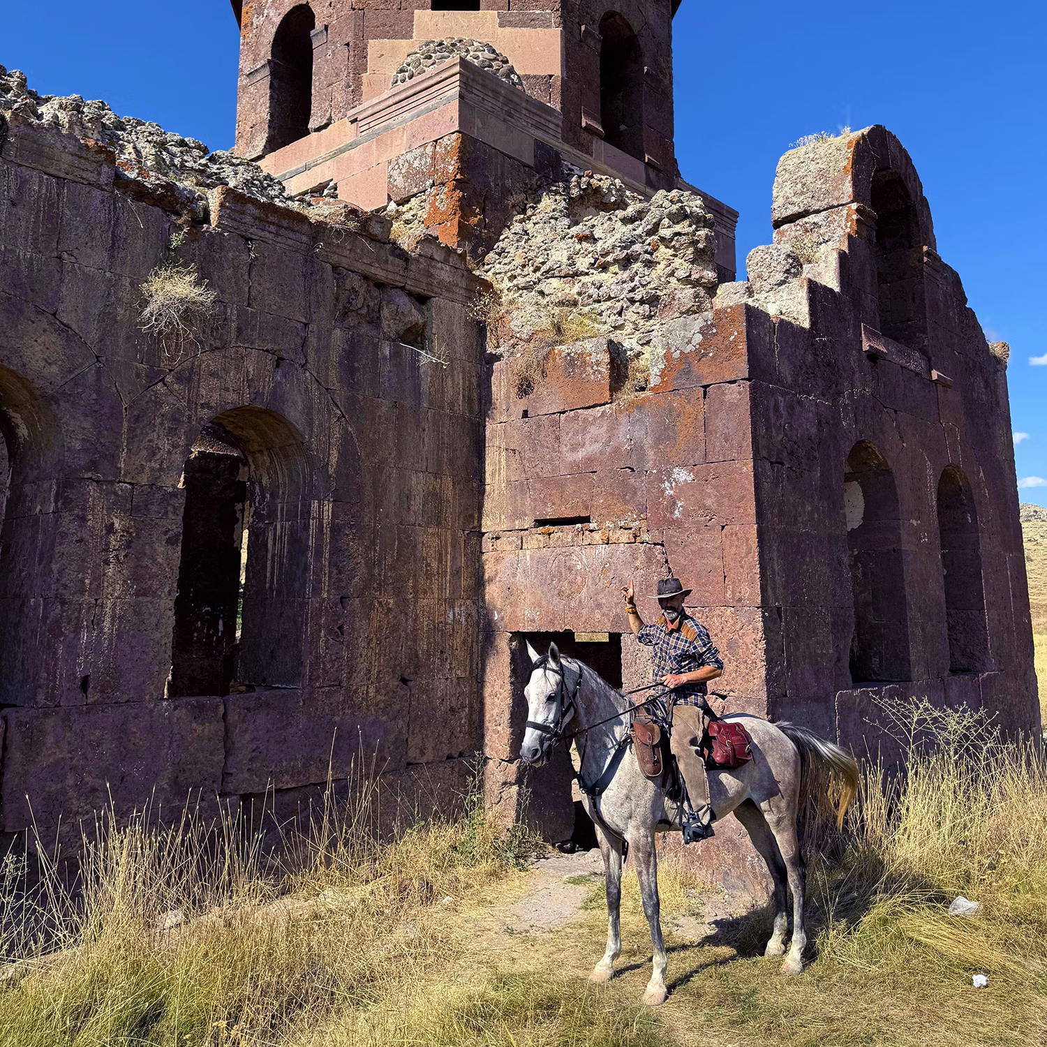 Un cavalier s’arrête devant les ruines en briques d’une ancienne tour.