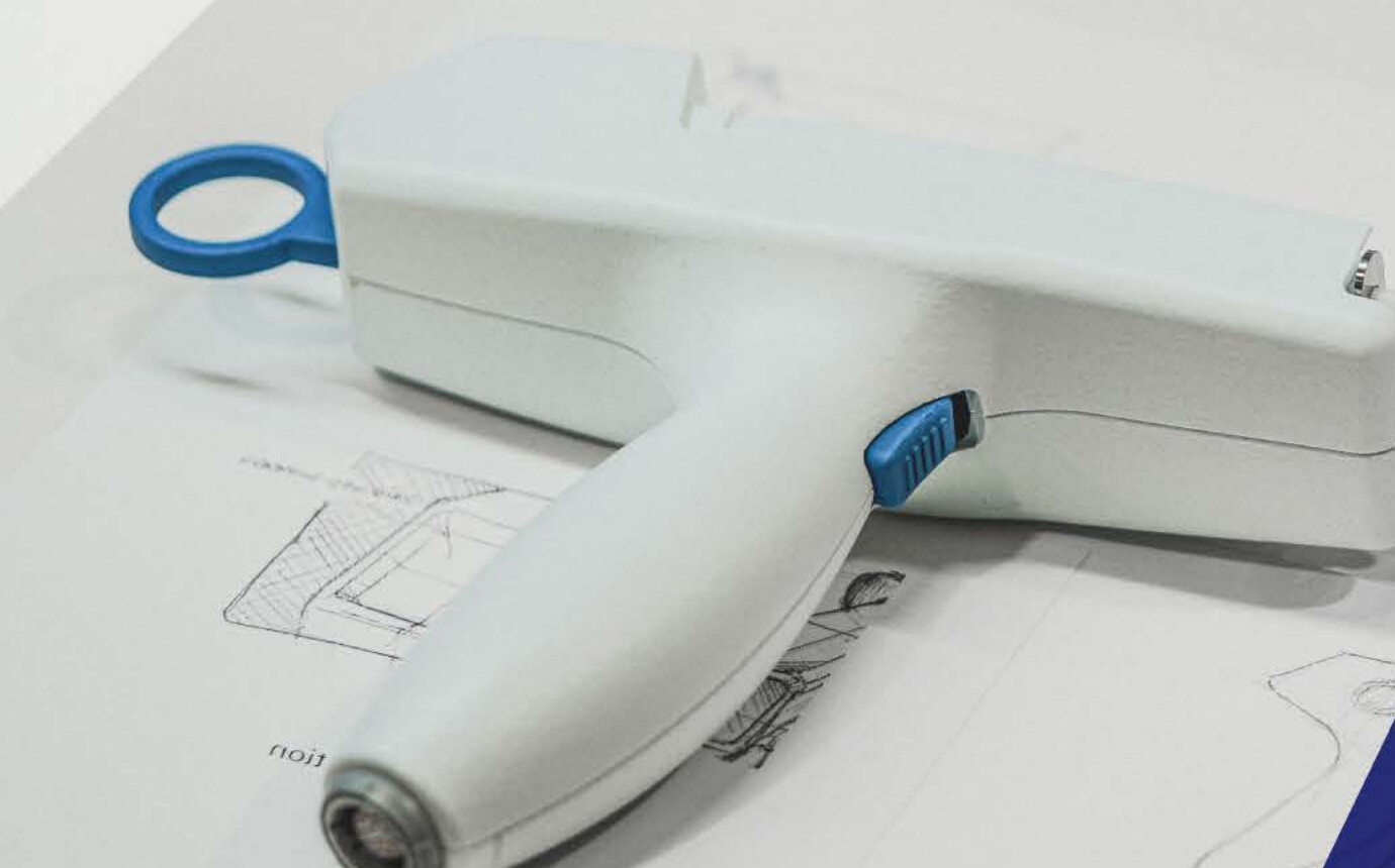 Electroporation delivery system handpiece prototype resting on engineering sketches.