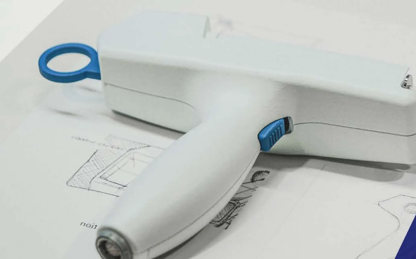 Electroporation delivery system handpiece prototype resting on engineering sketches.