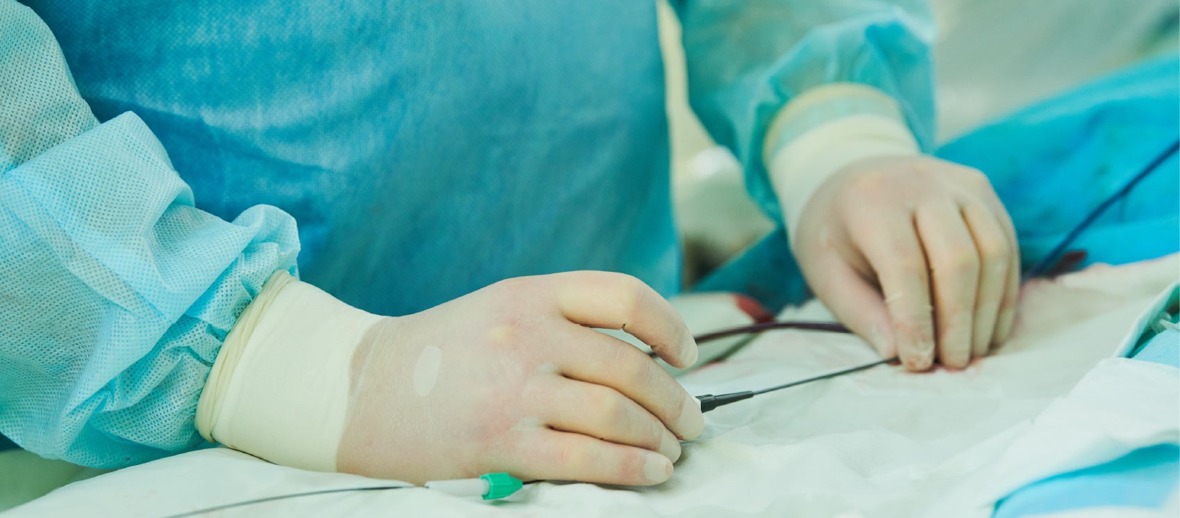 Cardiac catheterization lab team performing a coronary angioplasty, with live fluoroscopic images of the heart displayed on a large monitor overhead.