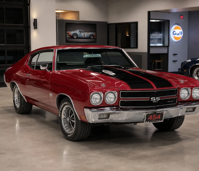 Red 1970 Chevrolet Chevelle SS muscle car with black racing stripes in a showroom during a classic car appraisal