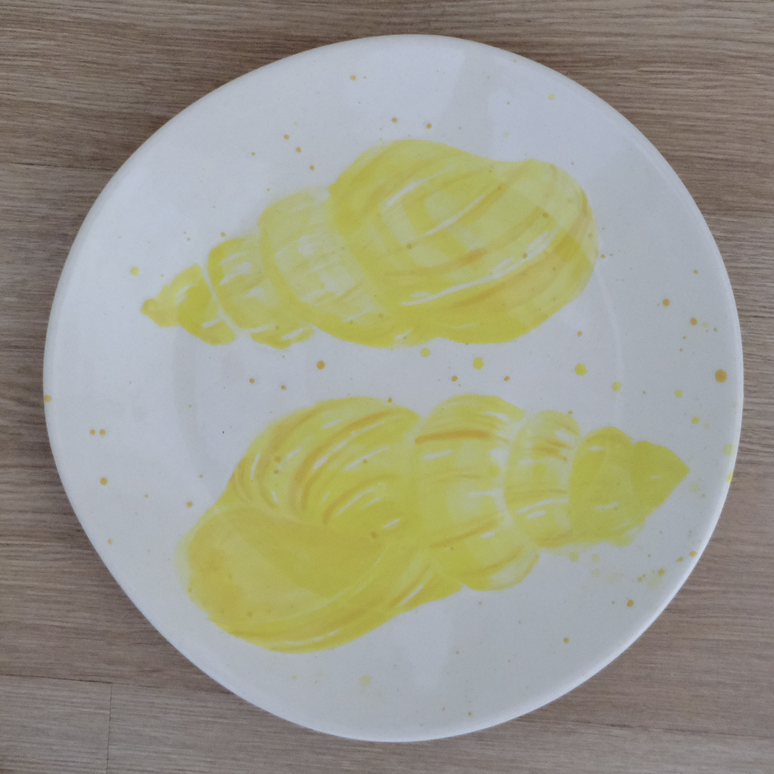 Hand-painted dinner plate with a yellow spiral shell