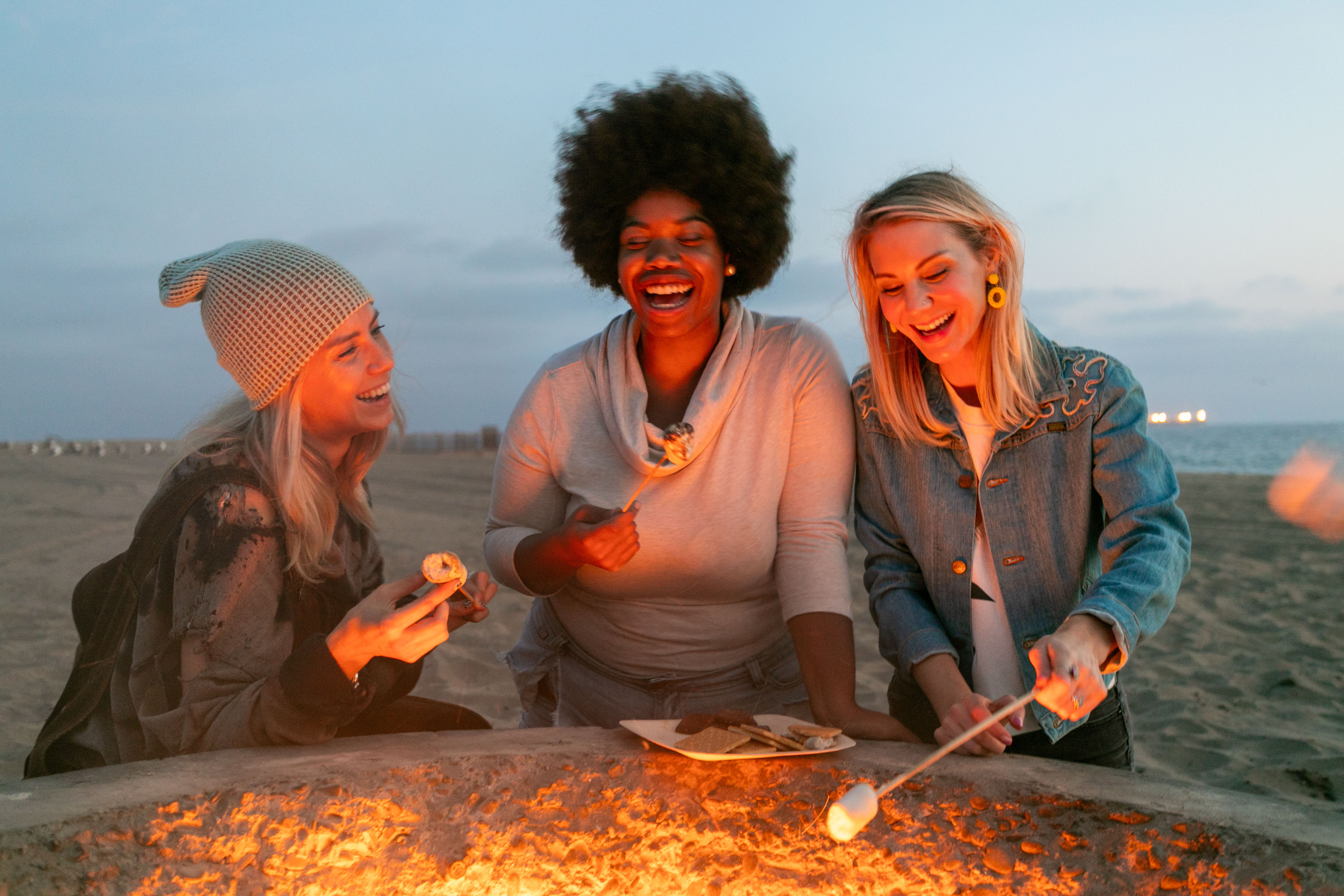 Women outdoors making s'mores over fire stock image