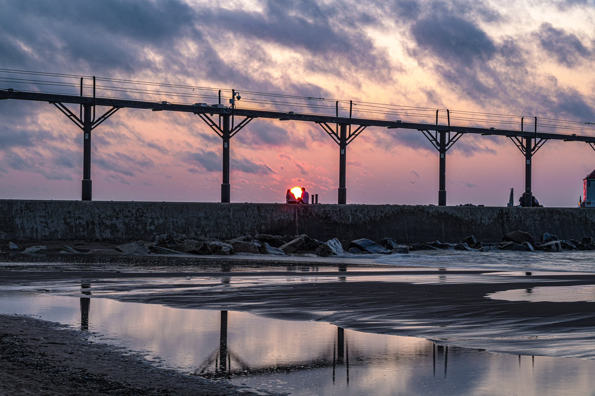 Sunset reflected in water along a pier.
