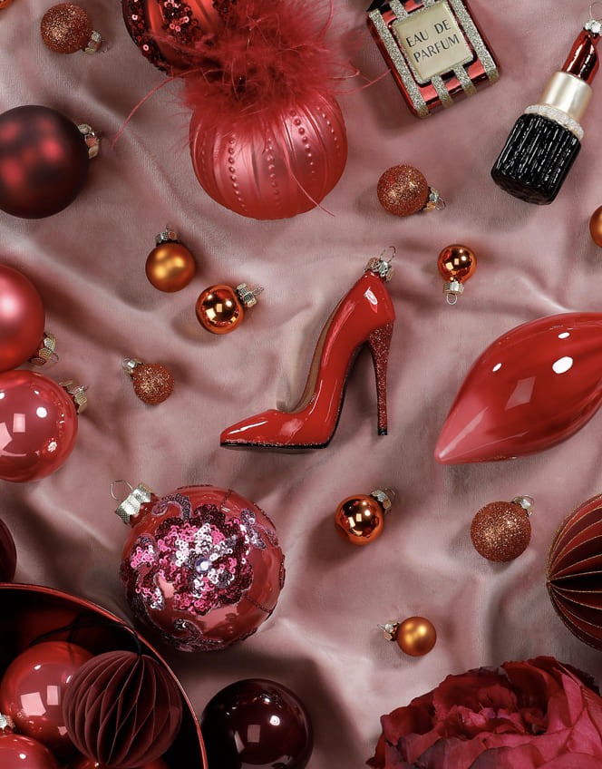 Rote und rosafarbene Weihnachtskugeln mit Glasornamenten in Lippen- und Schuhform.