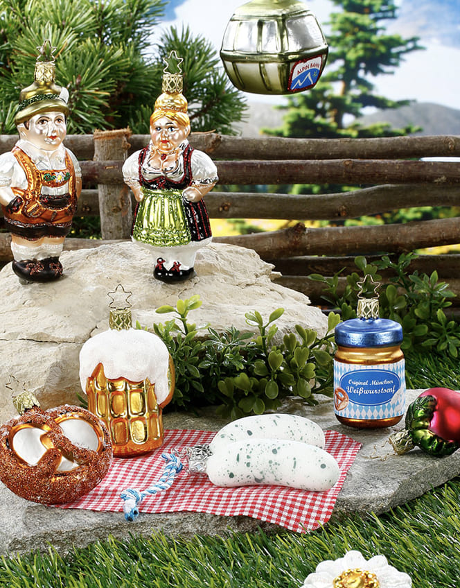 Figürlicher Christbaumschmuck mit Bierkrug- und Speisenmotiven auf einer gedeckten Tafel.