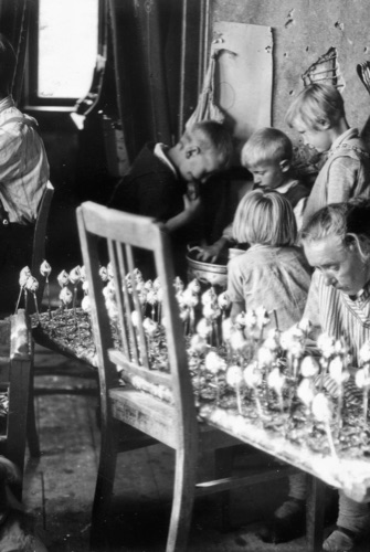 Historische Schwarzweißaufnahme einer Familie bei der Herstellung von Glasschmuck.