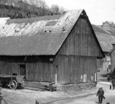Historische Schwarzweißaufnahme einer hölzernen Glashütte.