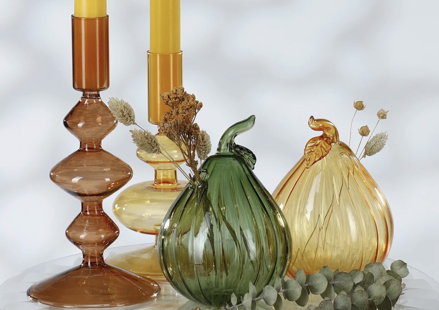 Braune und gelbe Glaskerzenhalter mit grünen und honiggelben Glasornamenten in Birnenform.