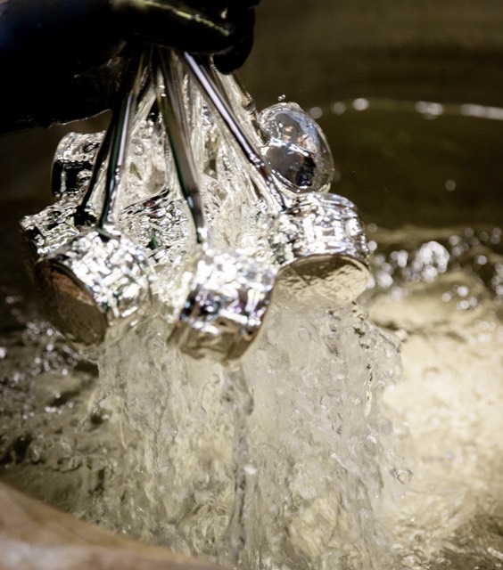 Klare Glasornamente an Haltestäben über einem Metallbehälter.