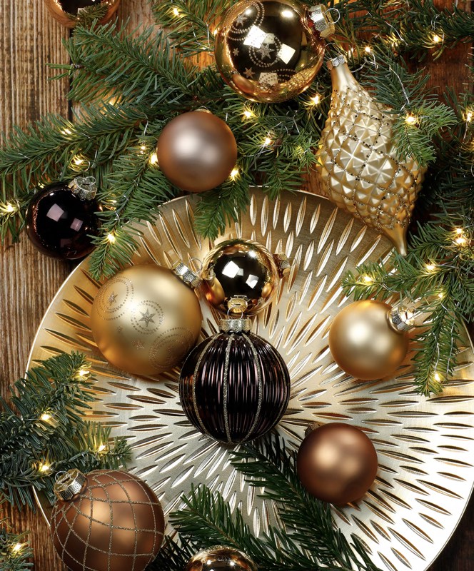 Goldene, braune und schwarze Weihnachtskugeln an einem Tannenzweig.