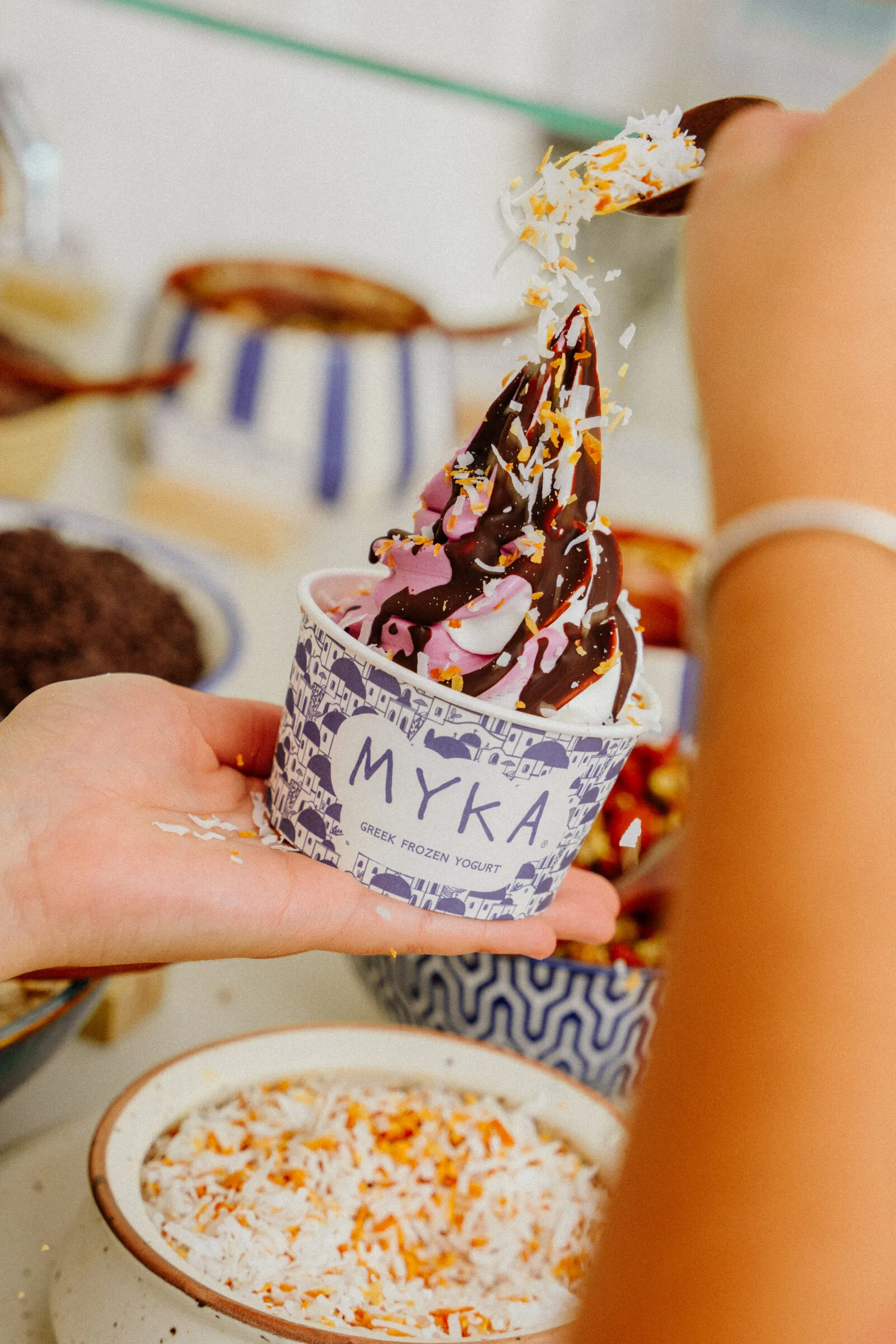 A branded MYKA cup being finished at the toppings bar.