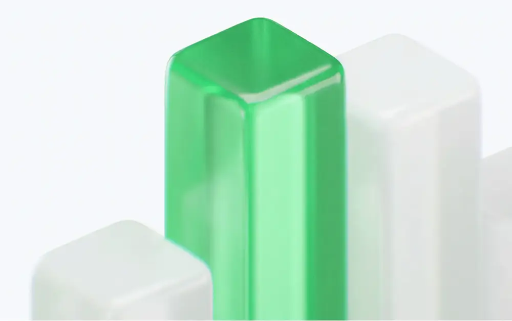 Close-up of a translucent green rectangular prism among white rectangular prisms on a light background.