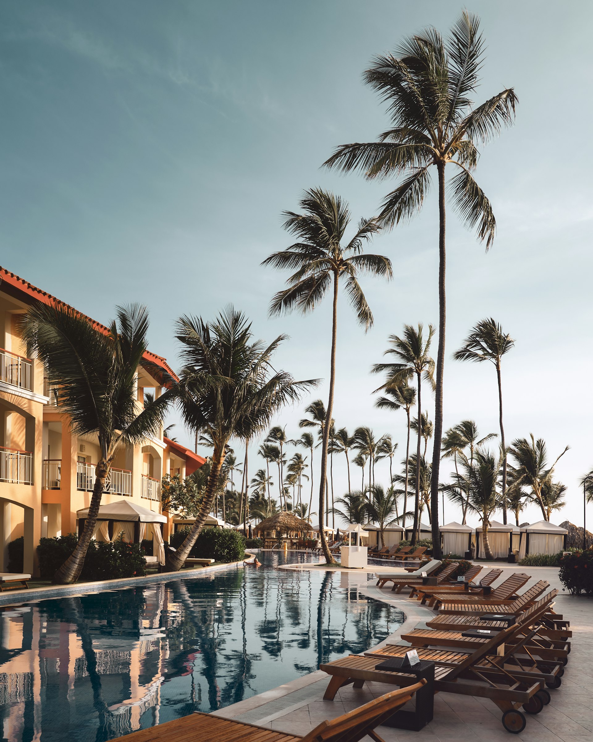 Wooden lounge chairs beside a hotel pool surrounded by palm trees, the kind of setting Miami hotels use for experiential marketing events. Photo by Christian Lambert on Unsplash.