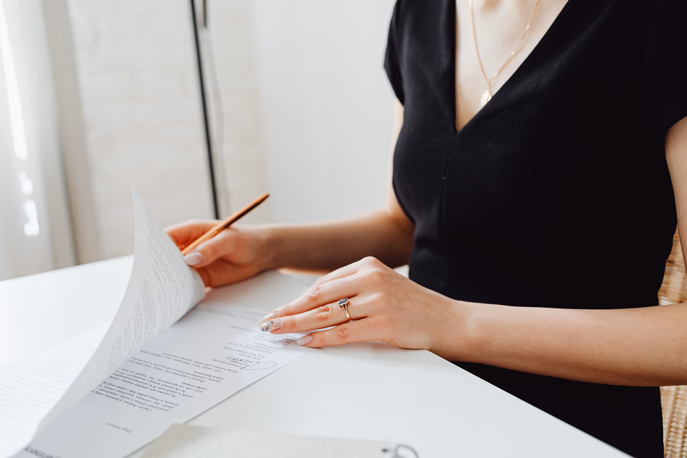 Woman in black dress making a Will at a white desk.