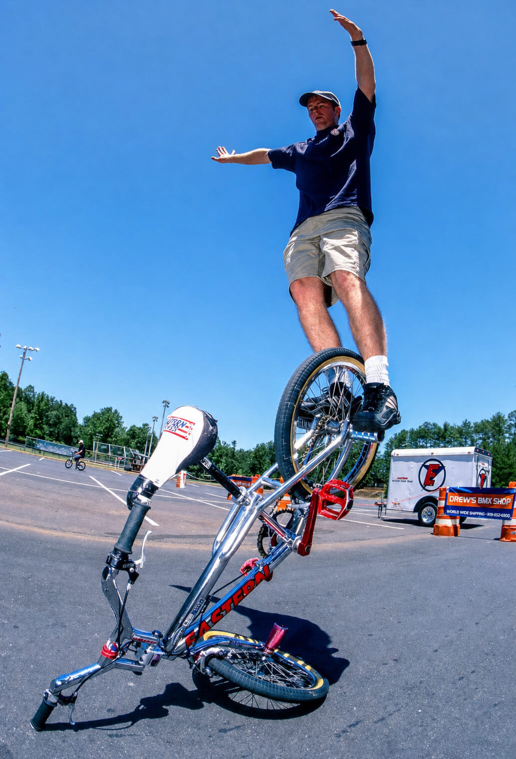 Keith King performing a BMX bike stunt on a sunny day in a parking lot.