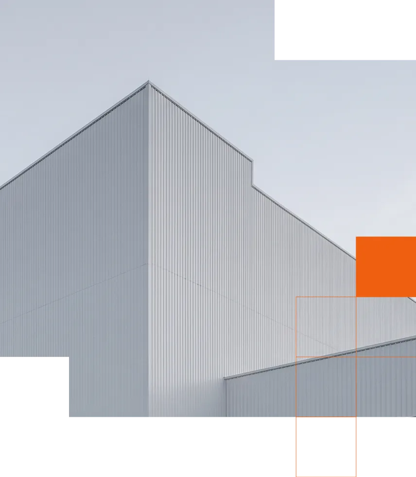 A modern industrial building with tall corrugated metal walls and a peaked roof against a pale gray sky.