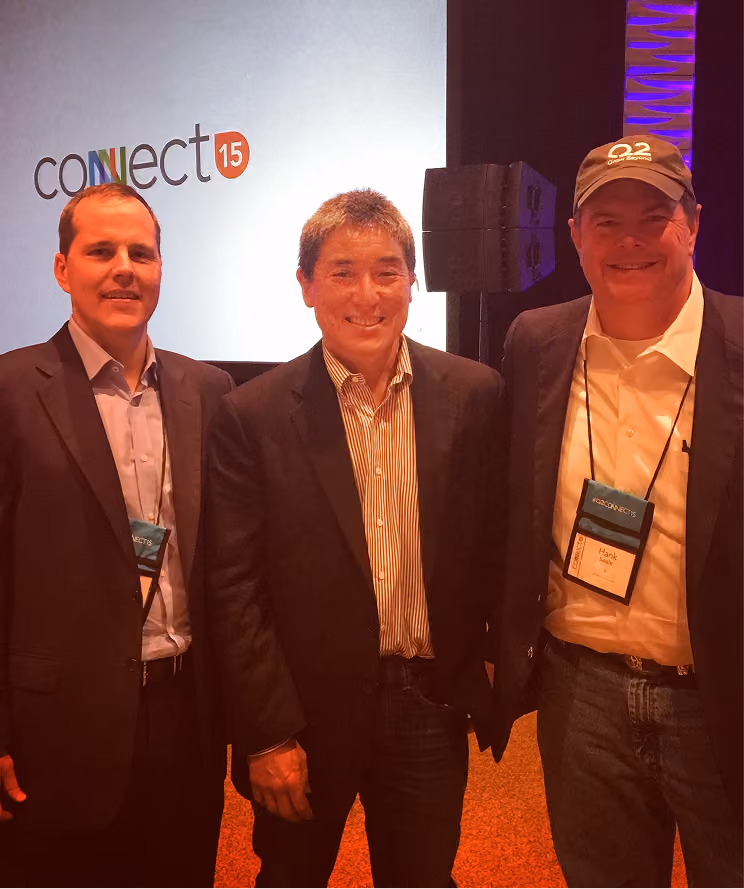Three men wearing blazers and conference badges standing in front of a Connect 15 event sign.