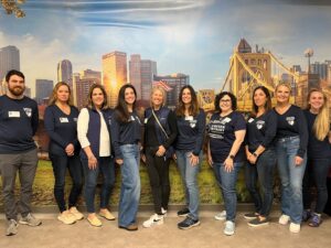 Ten volunteers in Simpson & McCrady gear taking a group photo at the Junior Achievement BizTown event