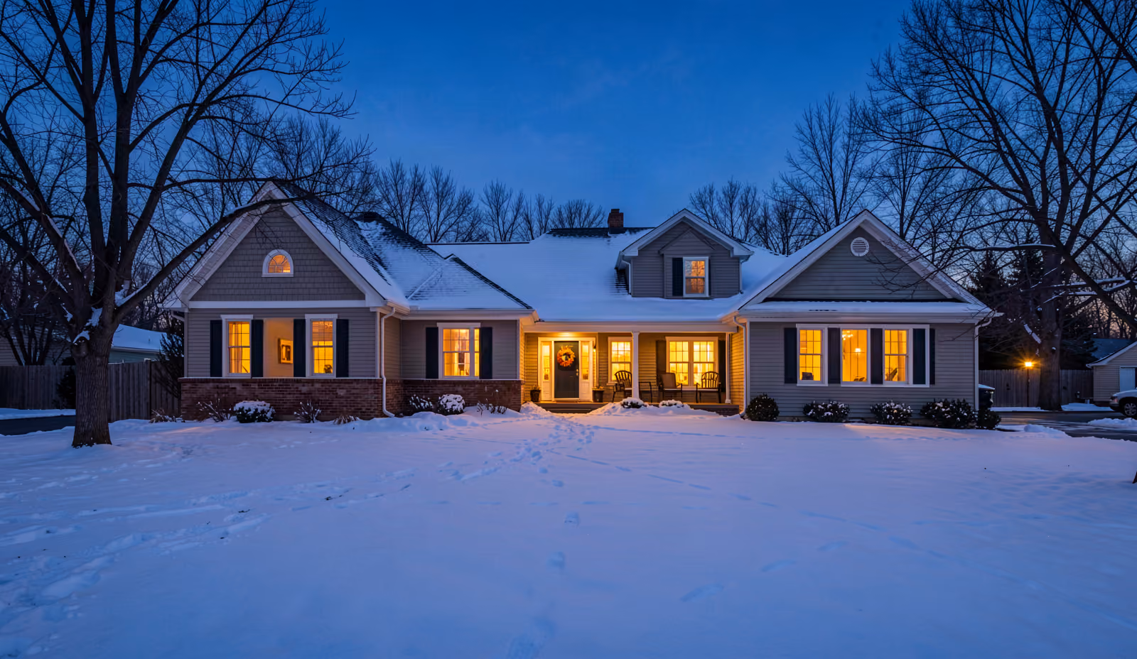 A welcoming home exterior at dusk in winter with warm light in the windows