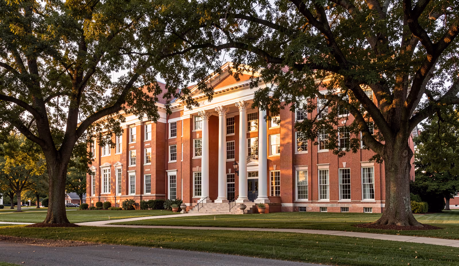 A historic brick civic institution building among mature trees