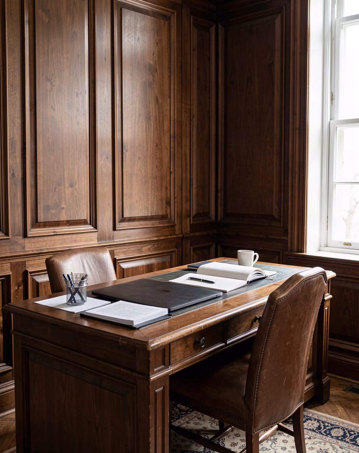 A private study with dark wood panelling, laptop and documents