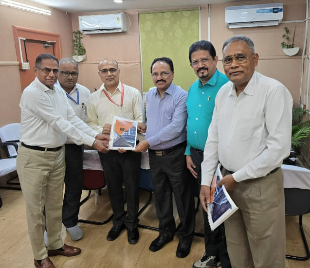 Six men in an office holding and presenting printed documents for a group photo.